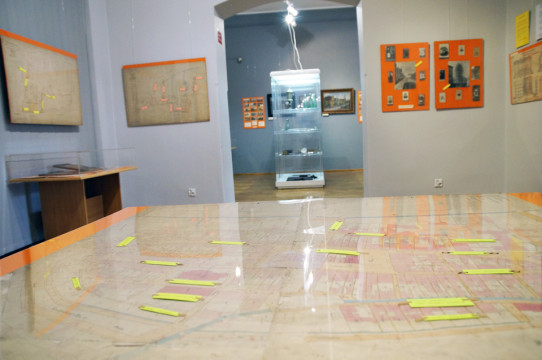 Fragment ekspozycji - na pierwszym planie widoczna część starej mapy Kluczborka, w tle wiszące antyramy z fotografiami i pocztówkami oraz gabloty z eksponatami.